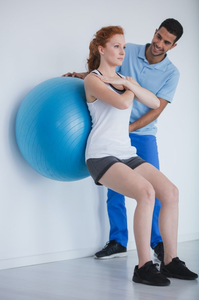 Female client working out with a ball during a training with a p